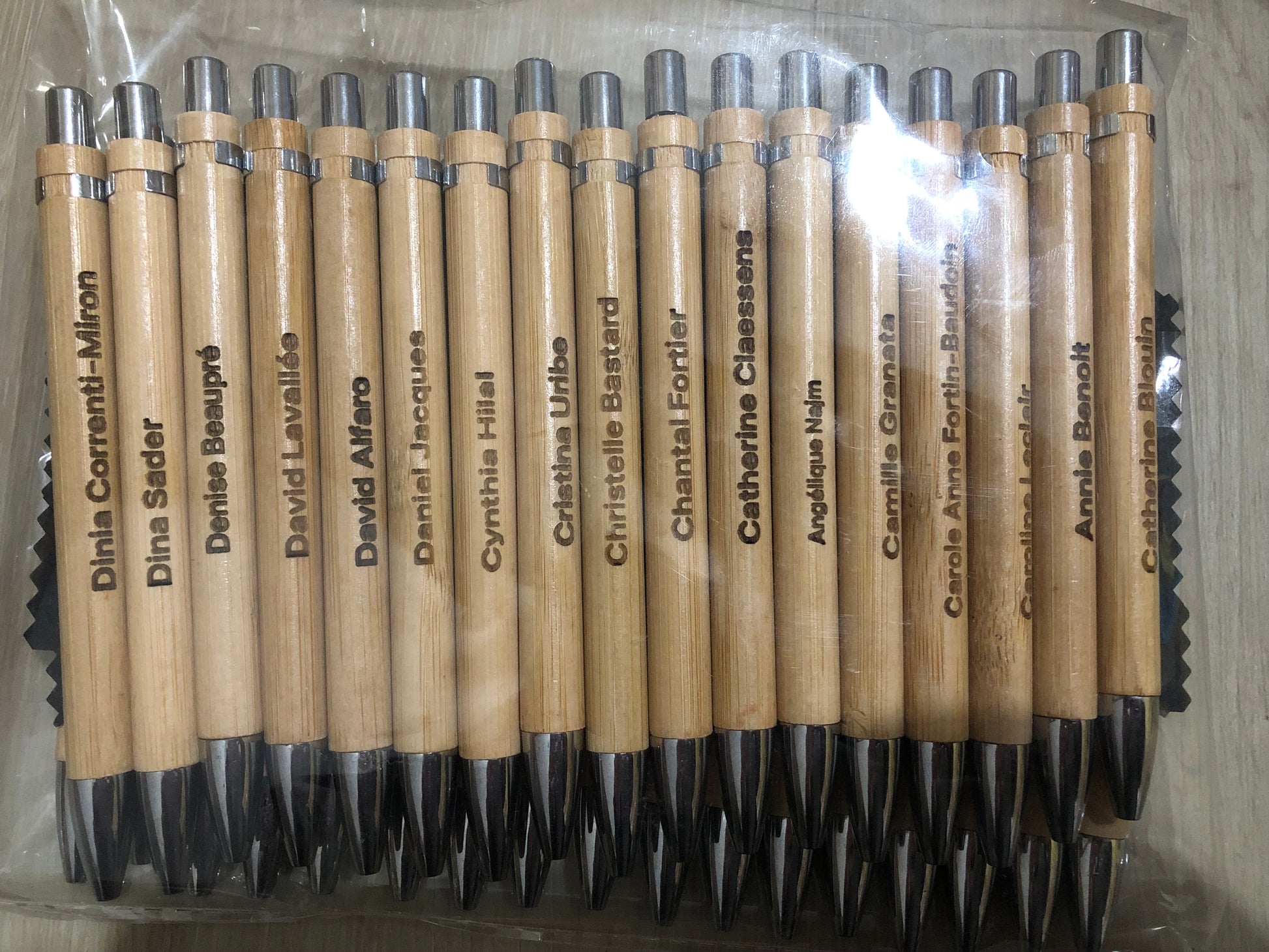 Set of wooden pens with names engraved on them, arranged in a clear plastic packaging.