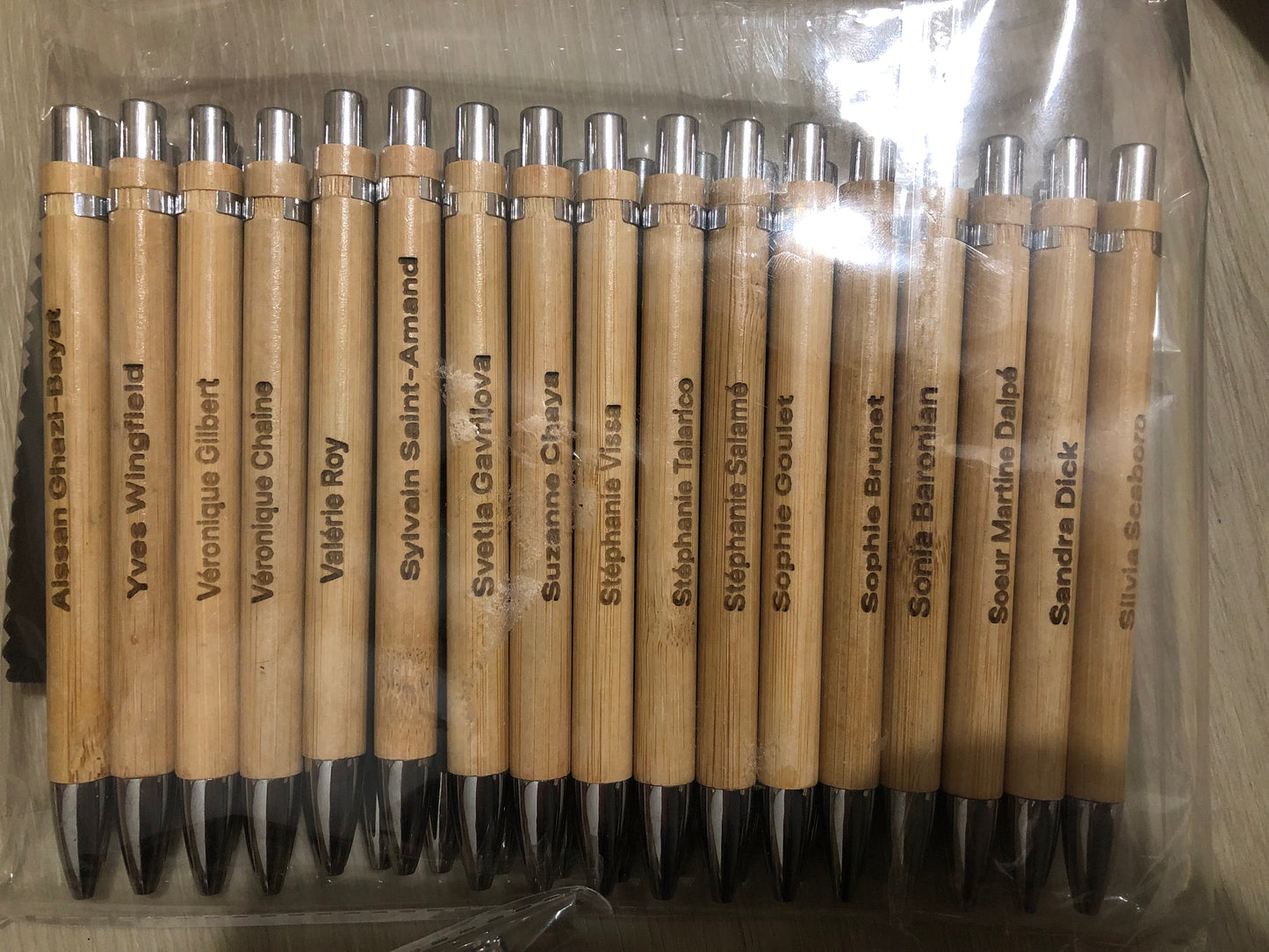 Set of wooden pens with names engraved on them, arranged in a clear plastic packaging.