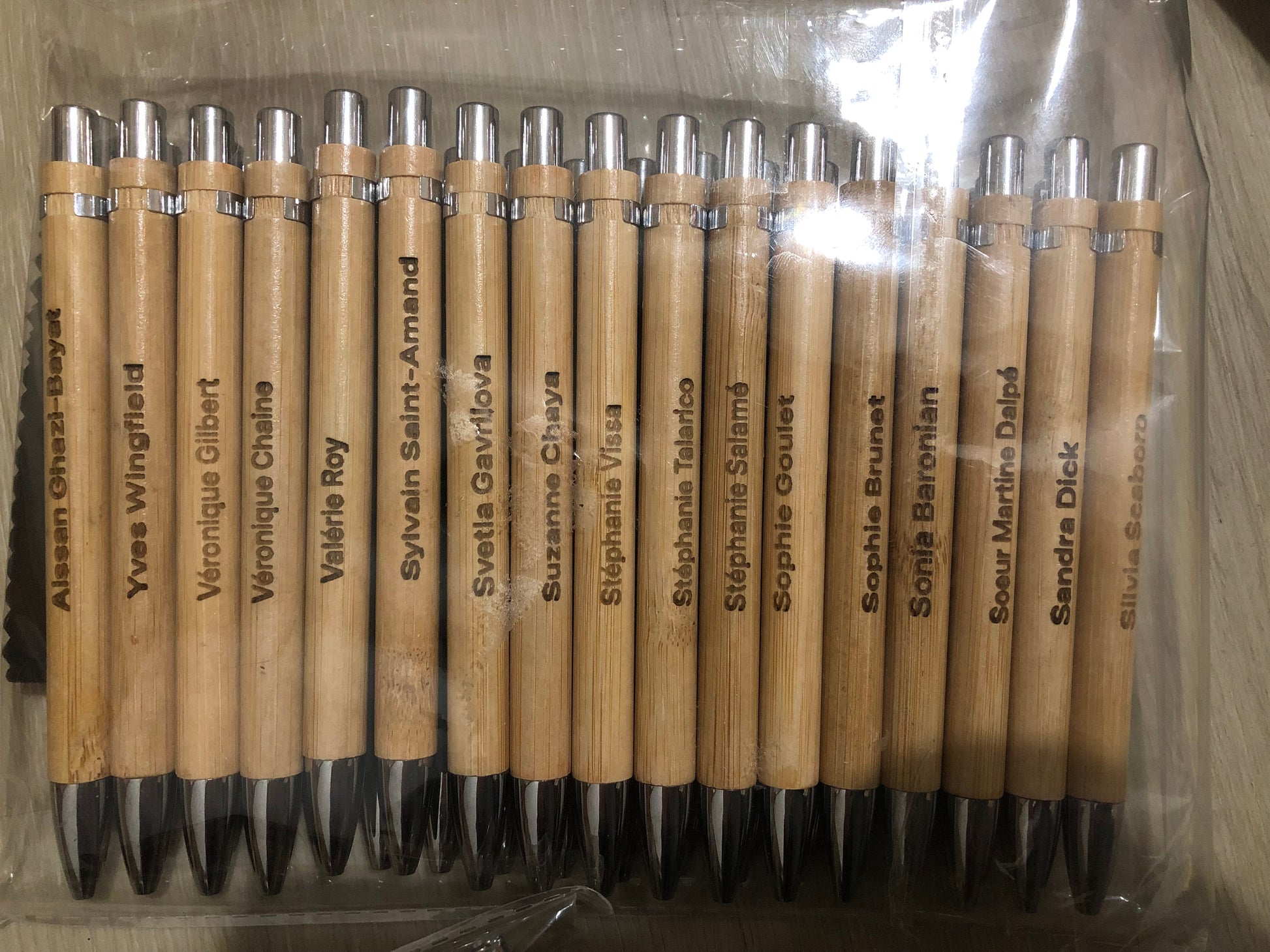Set of wooden pens with names engraved on them, arranged in a clear plastic packaging.
