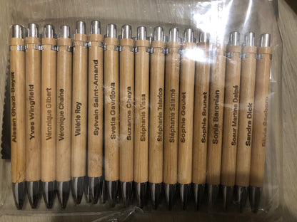 Set of wooden pens with names engraved on them, arranged in a clear plastic packaging.