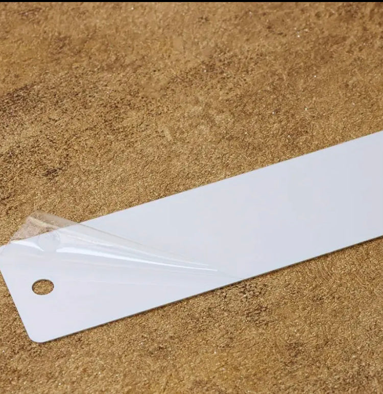 White metal bookmark  with a hole on a brown textured surface